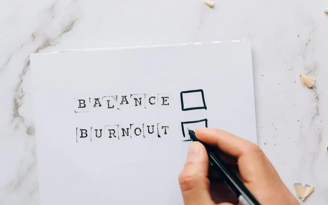 Close-up of a hand hovering over a checklist with options for balance or burnout, symbolizing stress and choice.